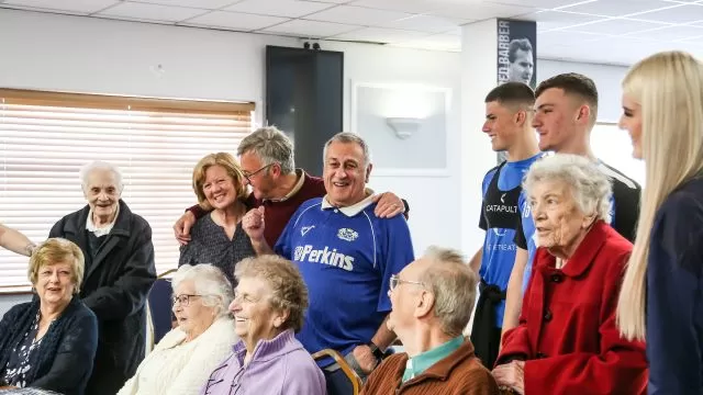 A group of people huddled together. Some people are standing, hugging or sitting down.