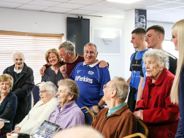 A group of people huddled together. Some people are standing, hugging or sitting down.