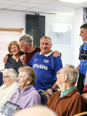 A group of people huddled together. Some people are standing, hugging or sitting down.