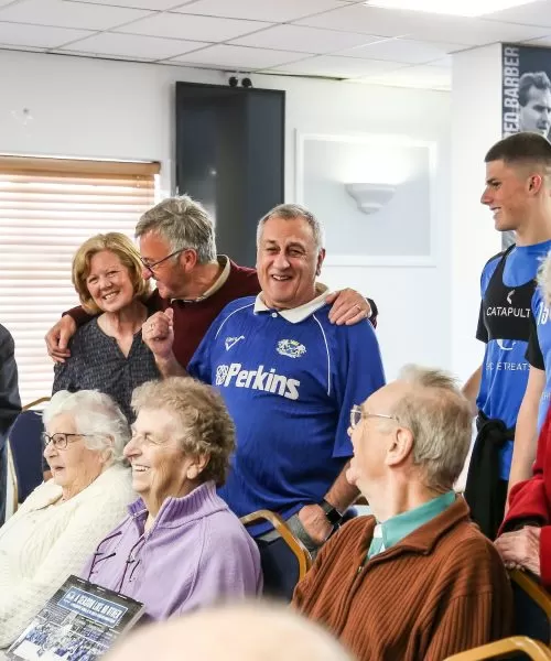 A group of people huddled together. Some people are standing, hugging or sitting down.