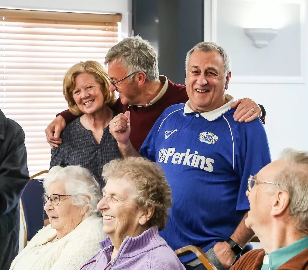 A group of people huddled together. Some people are standing, hugging or sitting down.