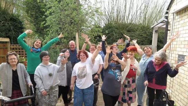 People standing together in a garden waving their hands in the air.