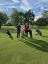 Four people standing huddled together facing the camera at a golf course.