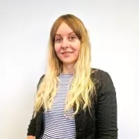 Headshot of Sara Marshall in a striped black and white top and black cardigan. She is standing in front of a white background.