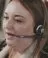 A close up shot of a helpline advisor mid-call, wearing a headset.