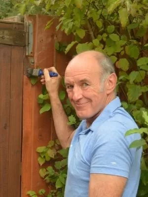 A person painting a wooden fence and gate.