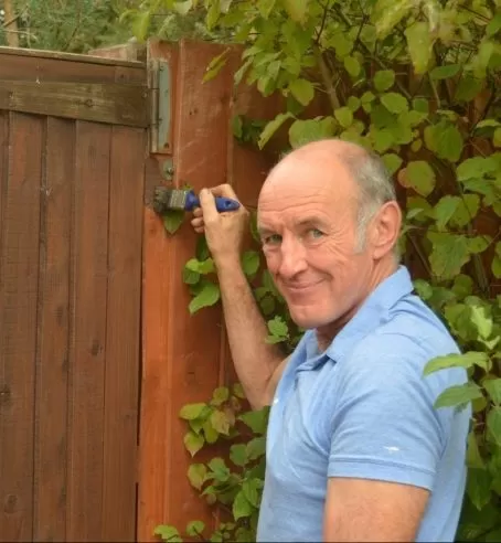 A person painting a wooden fence and gate.