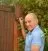 A person painting a wooden fence and gate.