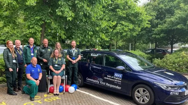 A group of medical professionals in uniforms by a Community First Responder car, with one person sitting on a Raizer chair.