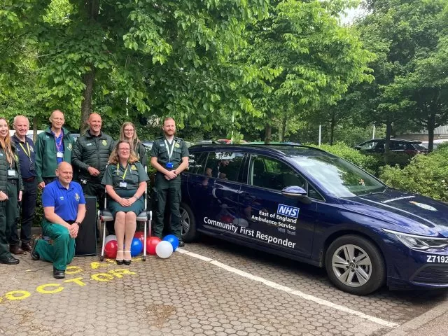 A group of medical professionals in uniforms by a Community First Responder car, with one person sitting on a Raizer chair.