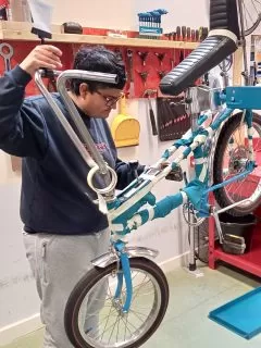 A person fixing a bike in an indoor workshop.