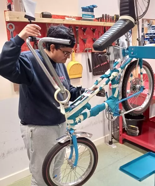 A person fixing a bike in an indoor workshop.