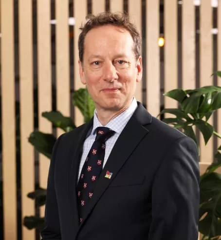 Headshot of Peter Burrows, CEO of The Cambridge Building Society, against a background of wooden panels and indoor plants.