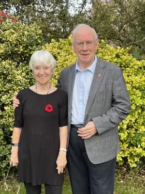 Stuart and Brenda Evans, the Foundation's supporters, standing in a garden in front of shrubbery.