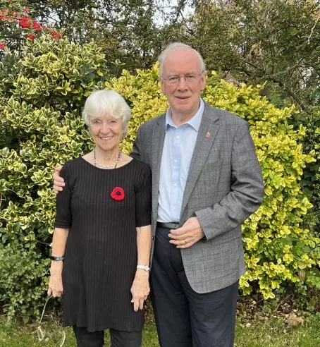 Stuart and Brenda Evans, the Foundation's supporters, standing in a garden in front of shrubbery.