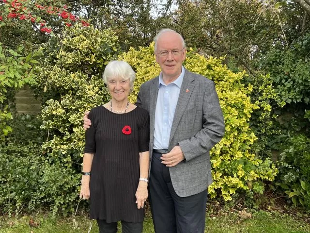 Stuart and Brenda Evans, the Foundation's supporters, standing in a garden in front of shrubbery.