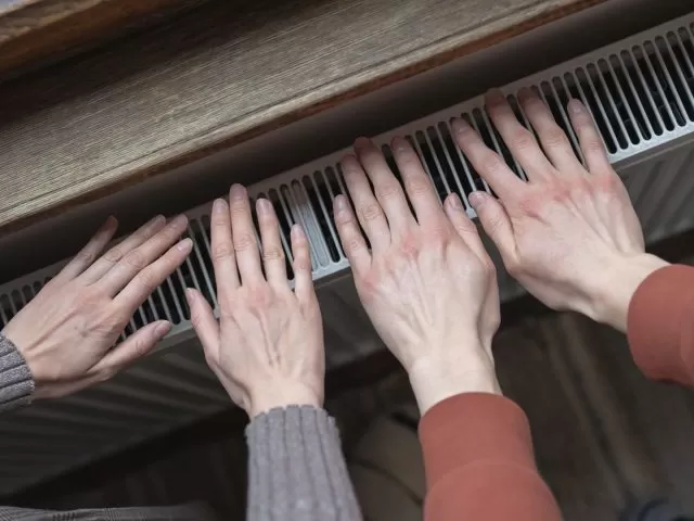 Two people's hands on top of a radiator.