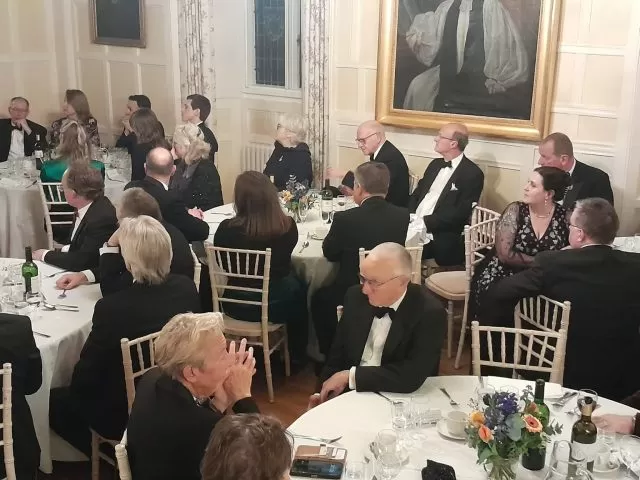 People seated at tables at a black tie event.