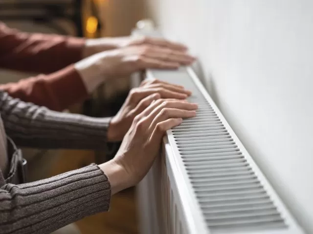 Two people's hands on top of a radiator.