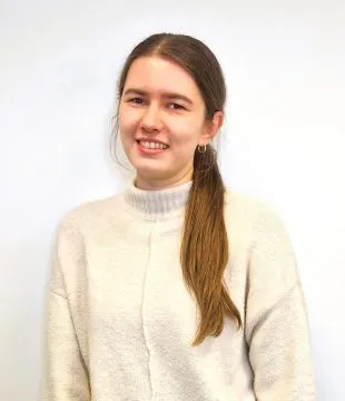 Headshot of Julia Cieslak in a cream jumper, standing in front of a white background.