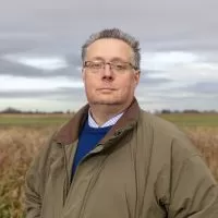A headshot of Michael Sly, Vice President of the Foundation, standing outside in a field.
