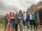 Women gathered together in a line outside in a green space with grey clouds.