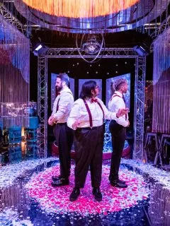 Three performers standing on a stage