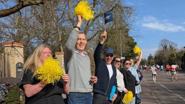 People cheering with yellow pom poms and paper hand flags with the Foundation's logo.